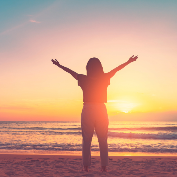 woman celebrating sunrise on beach