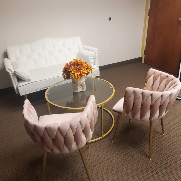 small white sofa with two pink chairs and a small round table in the center